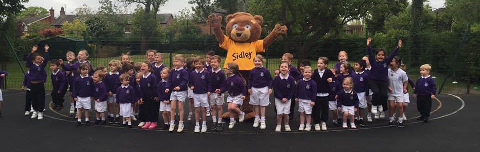 A group of children smiling with Sidley the bear